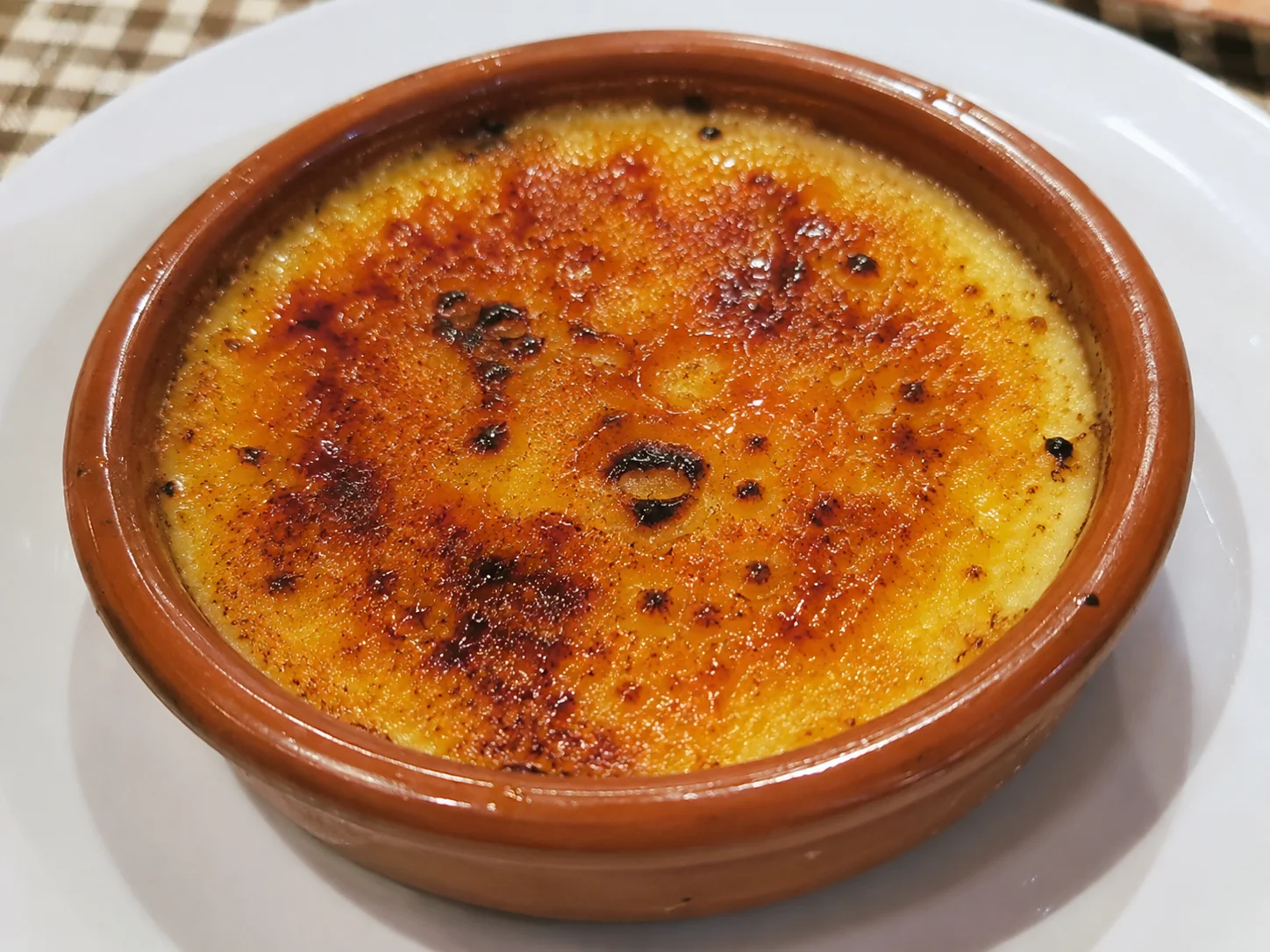 Crema catalana amb sucre caramel·litzat daurat acabada de cremar, en una cassola de fang