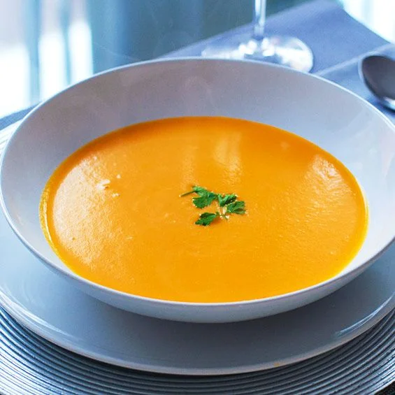 Bol de crema de carbassa sedosa amb un raig d'oli d'oliva i pipes de carbassa torrades per sobre