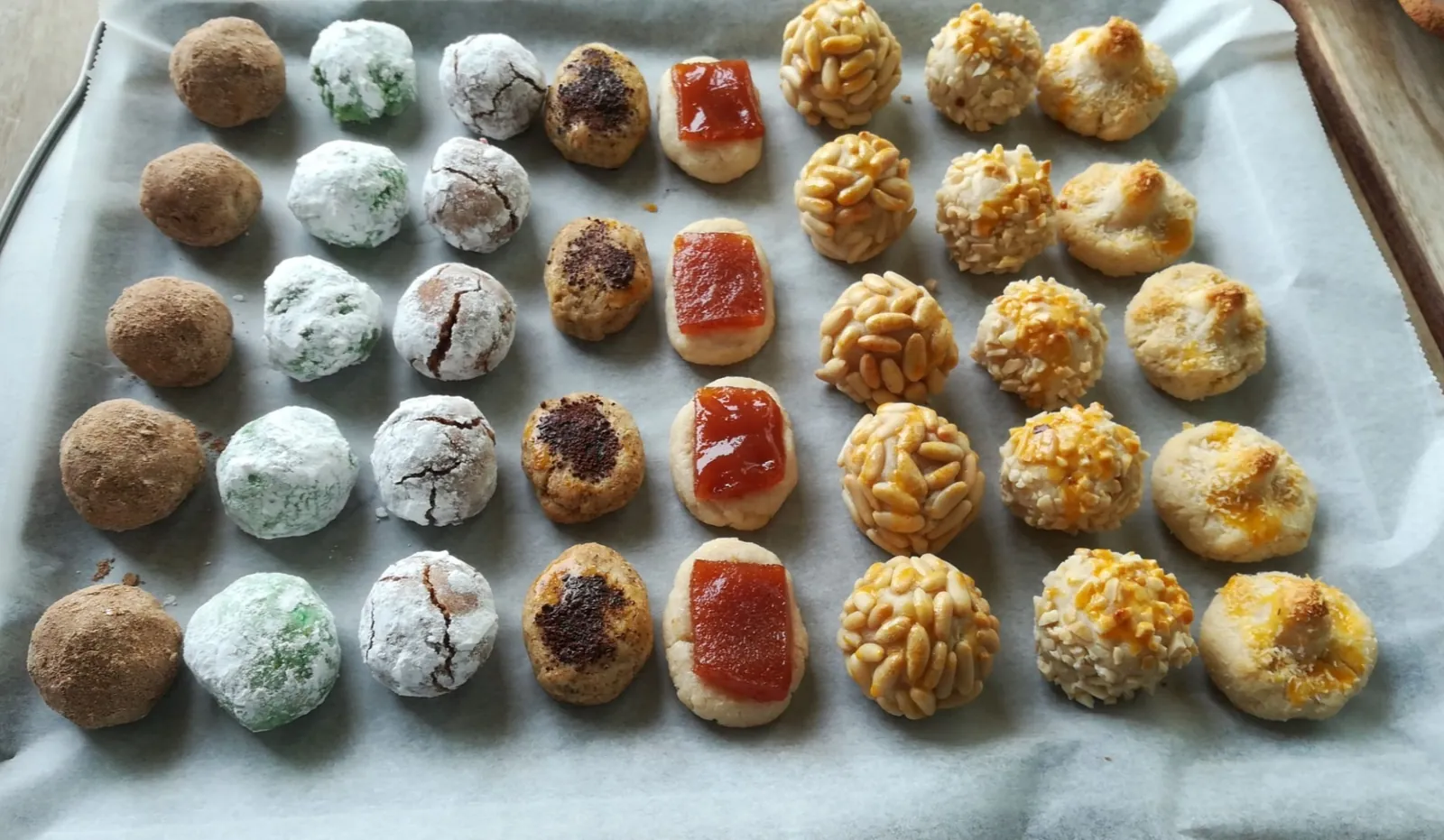 Safata de panellets de pinyons daurats al costat de panellets de coco, ametlla, cafè i xocolata